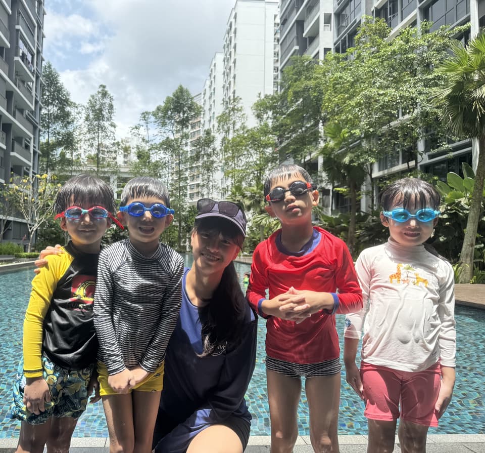 A Poolva coach with four smiling children in goggles beside a condo pool